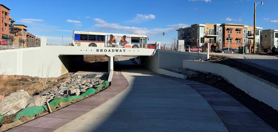 A bus drives over a bridge in a downtown area.