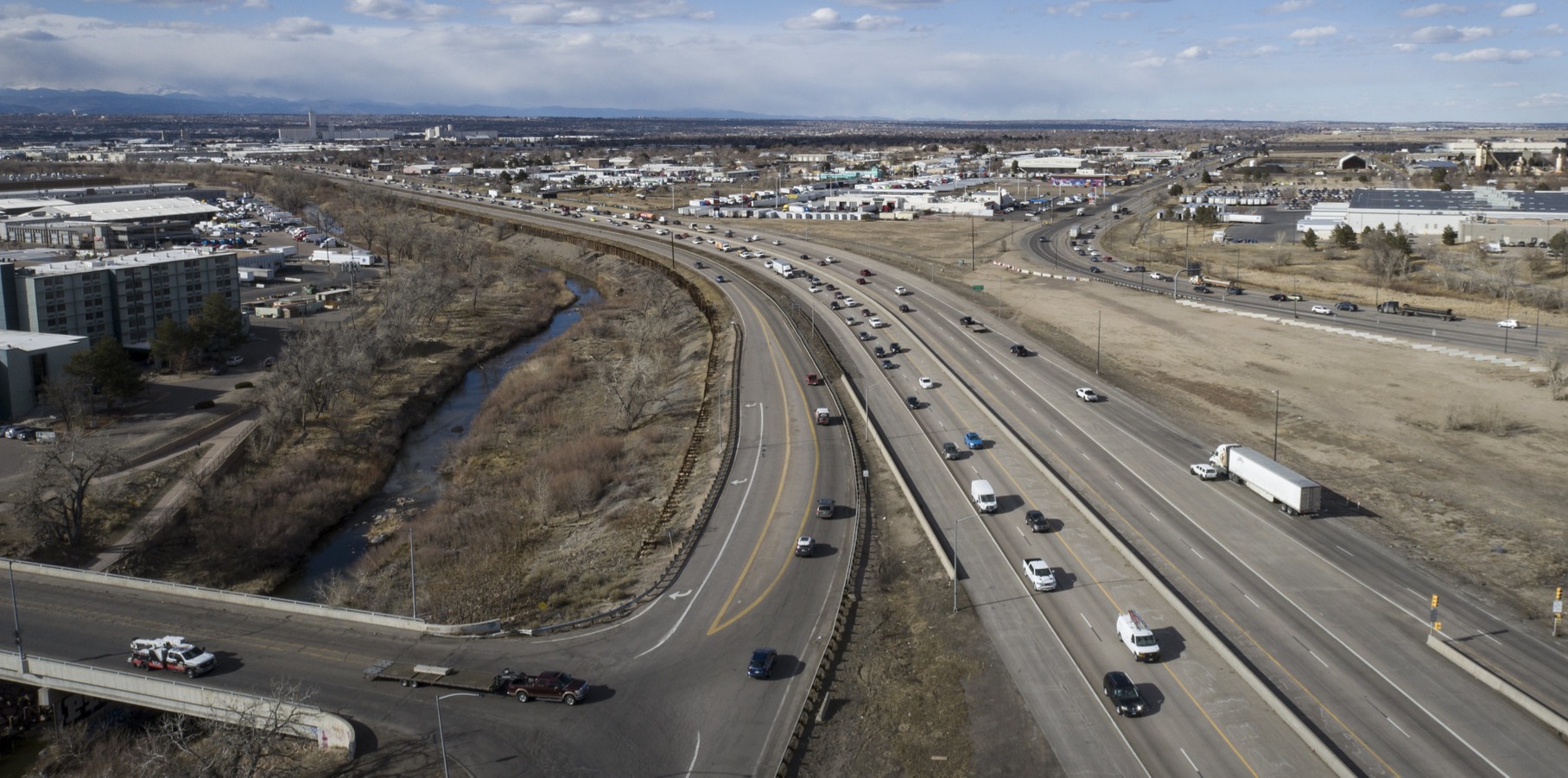 An aerival view of vehicles traveling on an interstate in an commercial area.