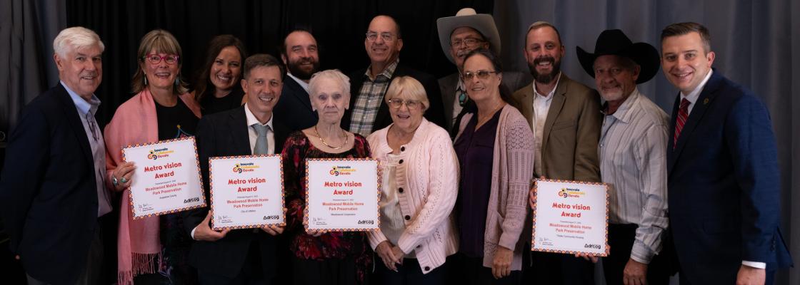 A group of residents and elected officials of all ages in business casual attire pose with their awards.