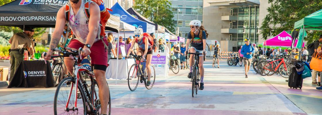 Bicyclist wearing helmets and casual attire arrive at Civic Center Station on a sunny sumemr day.