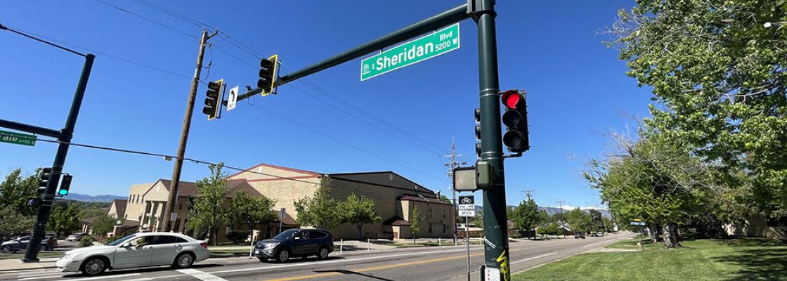 A white car and a dark-colored sport utility vehicle travel on Sheridan Boulevard.