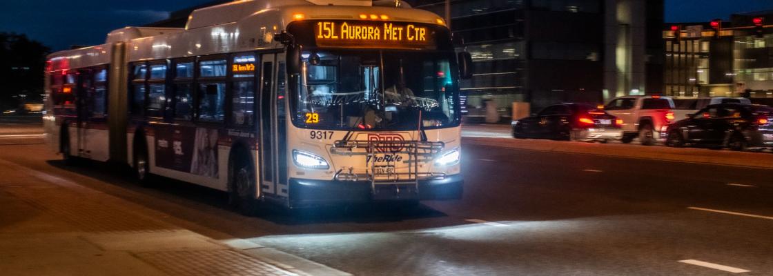 The route 15L double bus moves along Colfax Avenue in the evening. 